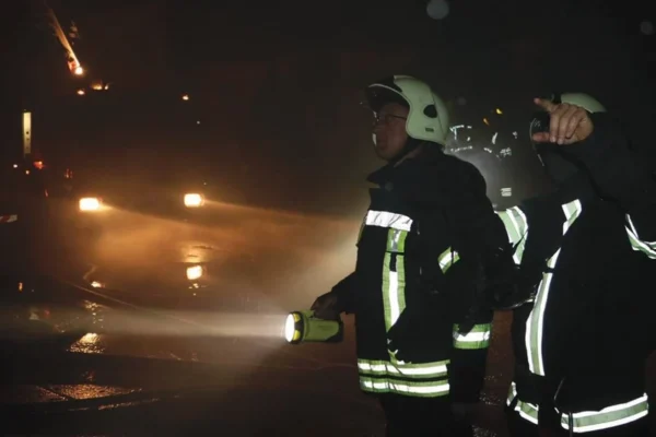 Firefighters using a handheld searchlight at night