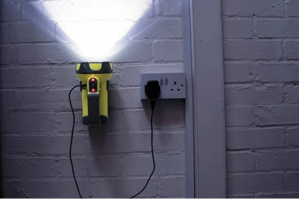 Yellow searchlight illuminating a wall while connected to a charger